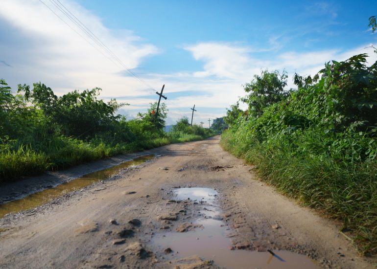 Einfache Straße mit vielen Schlaglöchern und Pfützen