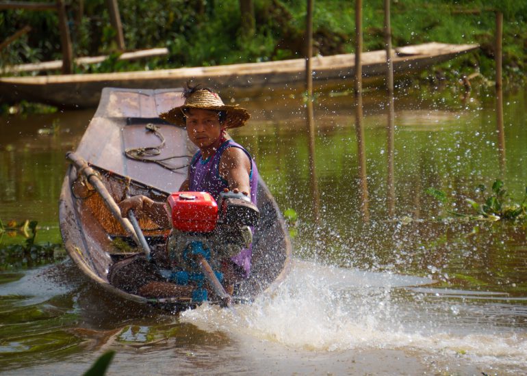 Burmese sitzt am Steuer eines Motorboots