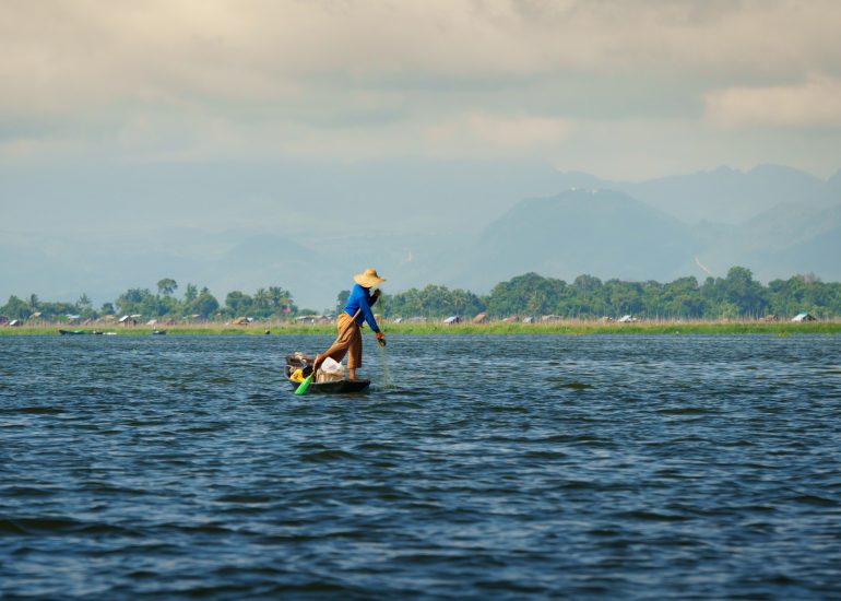 Mann mit Fischernetz auf Fischerboot auf dem Inle Lake