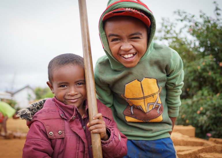 zwei kleine madagassische Kinder lachen in die Kamera