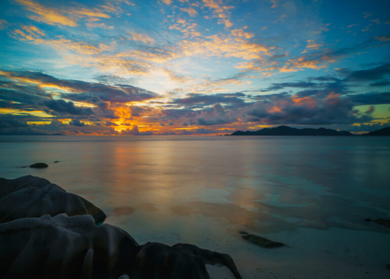 Sonnenuntergang auf La Digue mit Blick auf Praslin, feuerroter Himmel, Spiegelungen im Meer