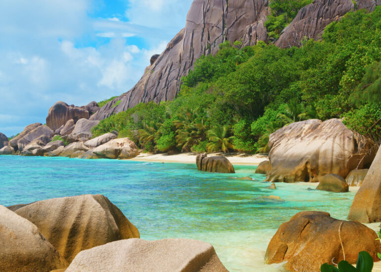 Strand mit vielen kleinen und einem riesigen Granitfelsen mit türkisblauem Meer